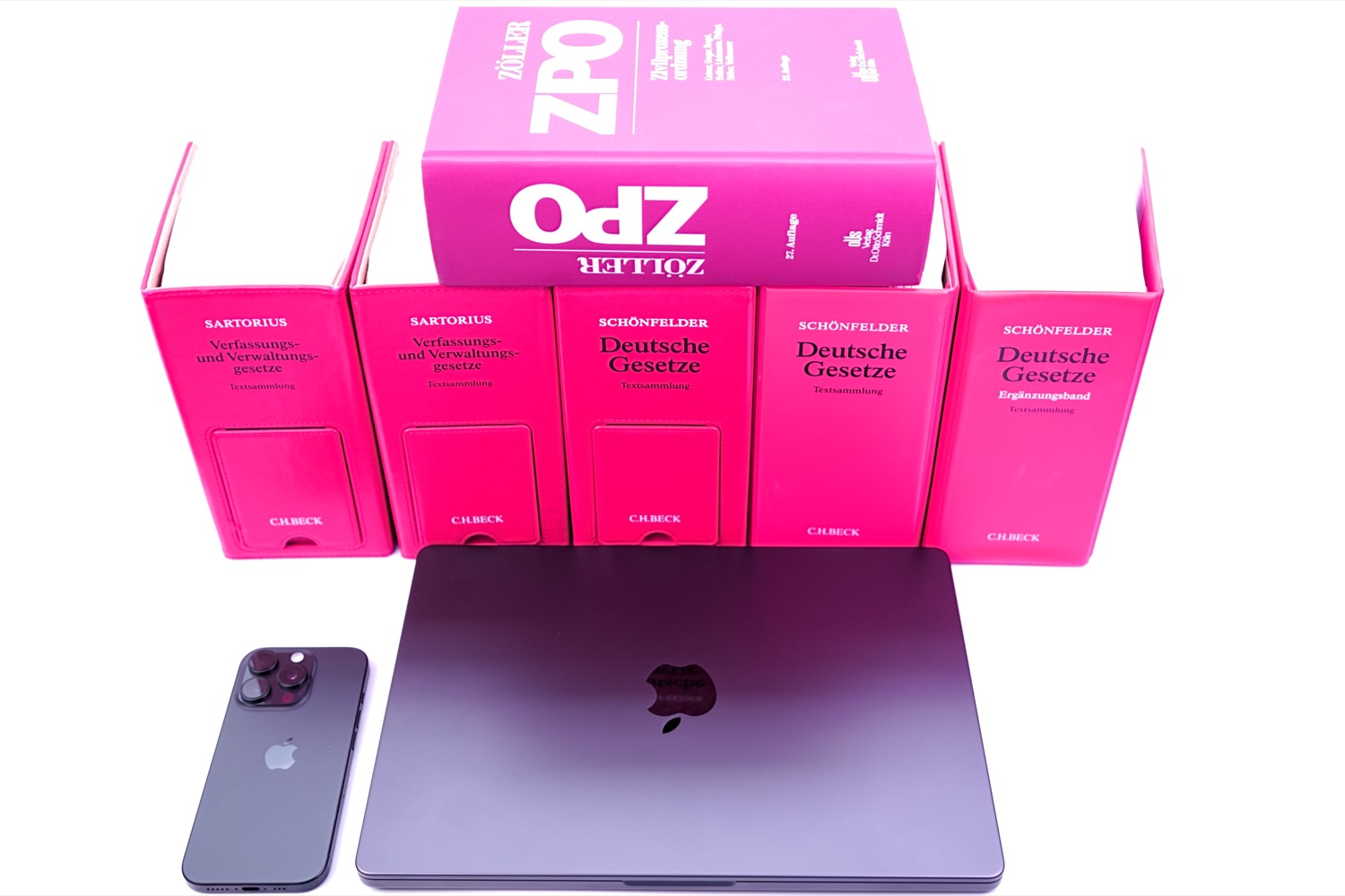 Gesetzessammlungen Zöller, Sartorius und Schönfelder neben einer weißen Orchidee und einem Smartphone. Symbole für juristisch
